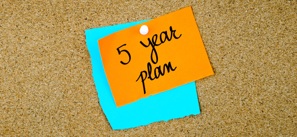 Five Year Plan written on paper notes pinned on cork board with white thumb tack
