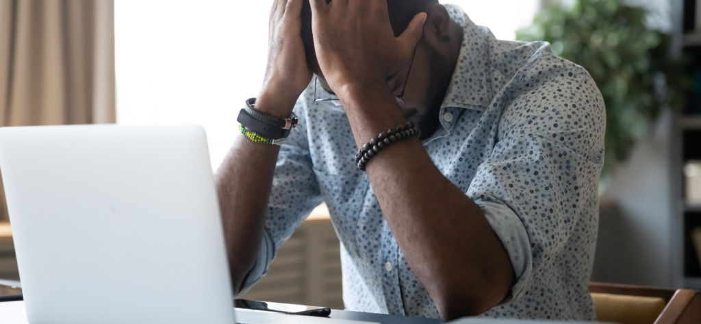 a person sitting at a desk with their head in their hands