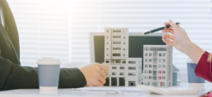 two business people pointing at 3D model of buildings on table